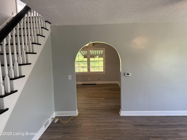 interior space with baseboards, a textured ceiling, wood finished floors, and stairway