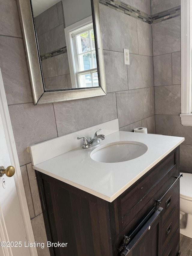 half bath with vanity, toilet, and tile walls
