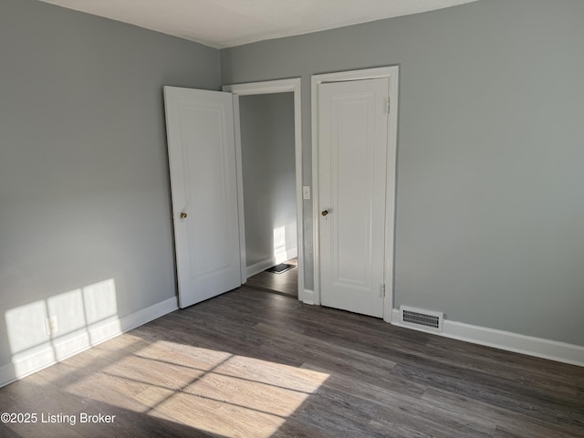 unfurnished bedroom with visible vents, baseboards, and wood finished floors