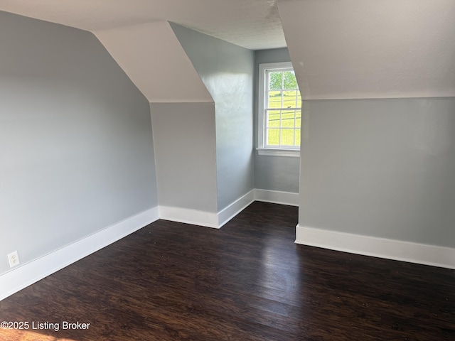 bonus room featuring dark wood-type flooring, baseboards, and lofted ceiling