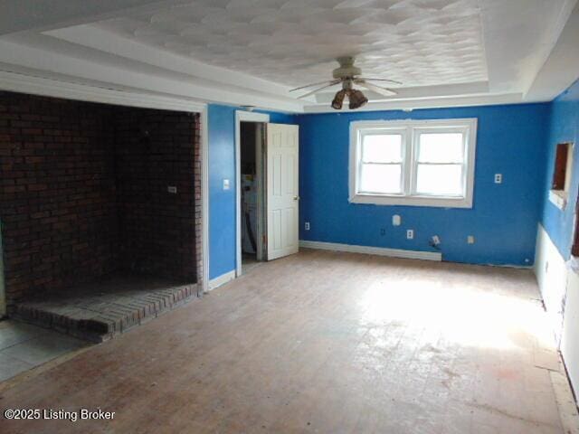 unfurnished bedroom with baseboards, a tray ceiling, two closets, and a ceiling fan