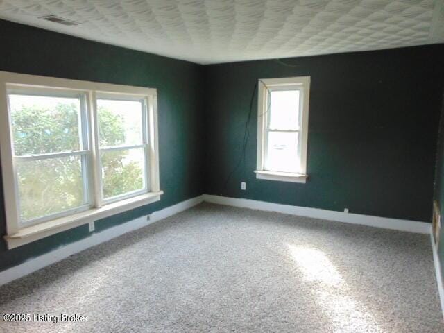 carpeted spare room with visible vents and baseboards