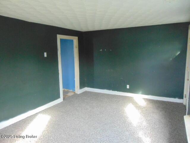 carpeted empty room featuring baseboards