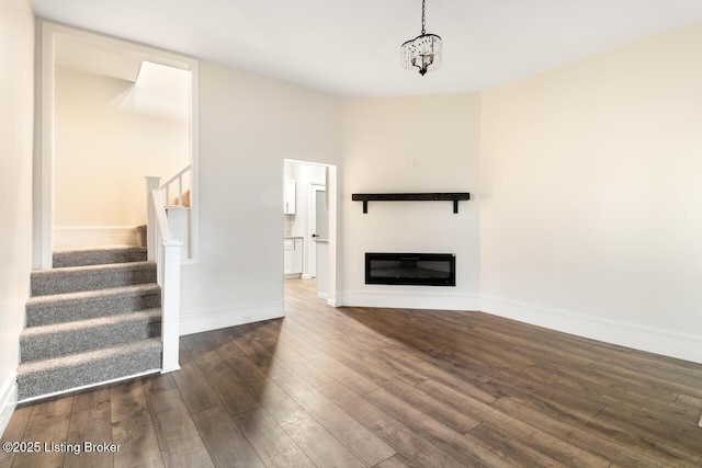 209 W High St, Lebanon, KY 40033 - unfurnished living room with wood finished floors, baseboards, stairway, a notable chandelier, and a glass covered fireplace