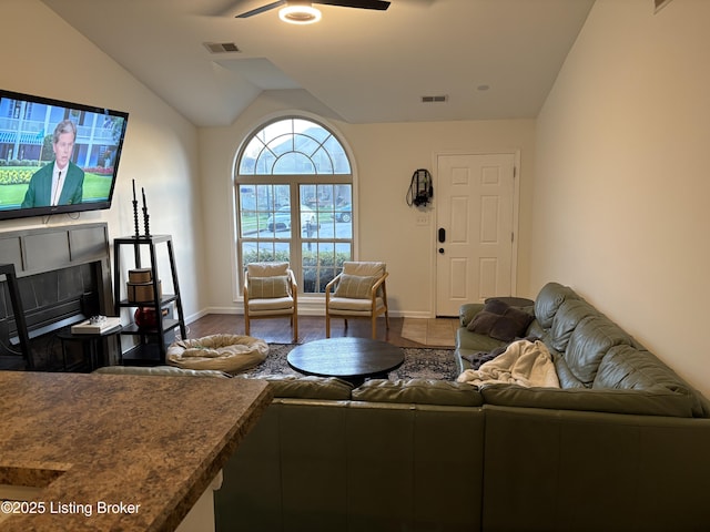 living room with a ceiling fan, baseboards, and vaulted ceiling