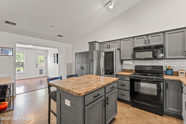 kitchen featuring black appliances, gray cabinets, decorative backsplash, light countertops, and a kitchen island