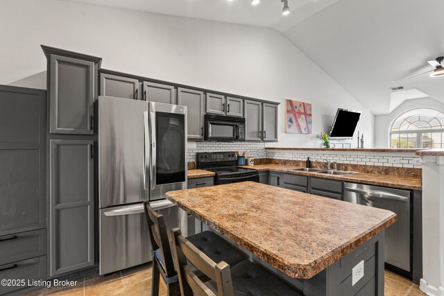 kitchen with black appliances, a sink, vaulted ceiling, and gray cabinetry