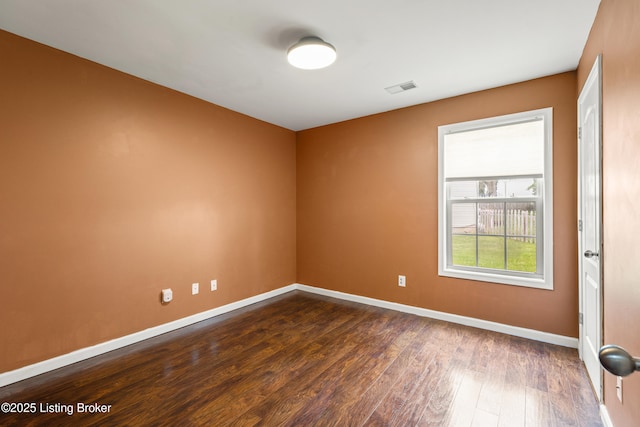 spare room with baseboards and dark wood-style floors