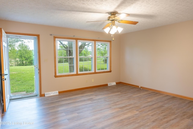 unfurnished room with a wealth of natural light, light wood finished floors, and visible vents