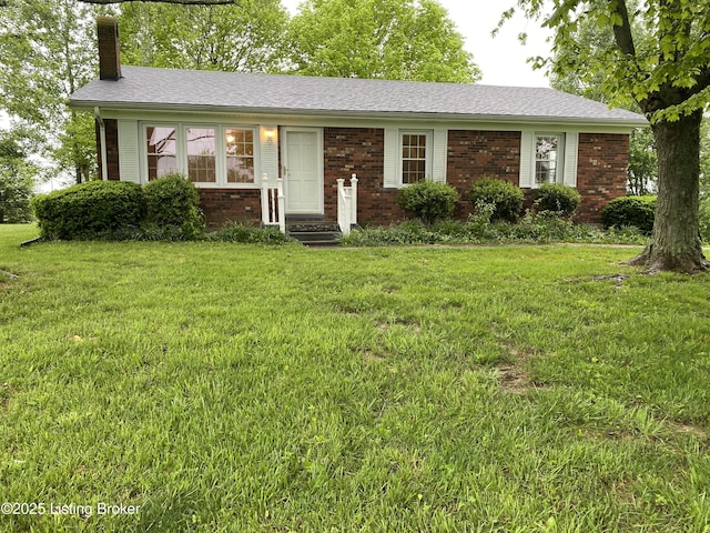 view of front of property with a chimney, a front lawn, and brick siding