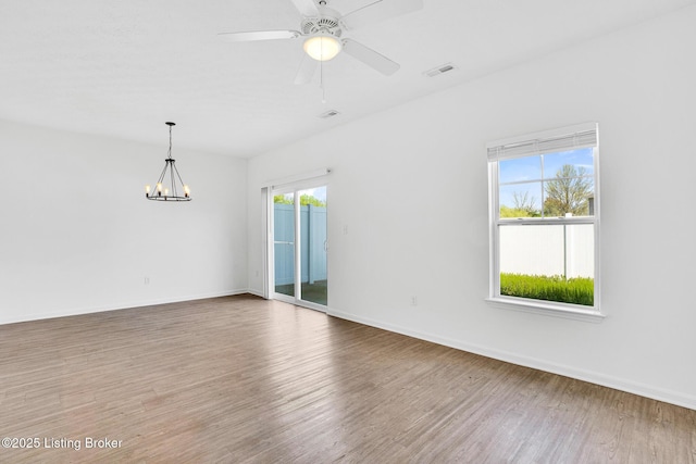 unfurnished room with baseboards, visible vents, wood finished floors, and ceiling fan with notable chandelier