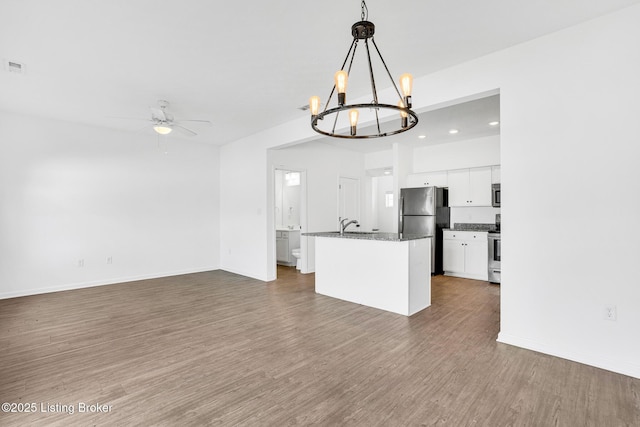 kitchen with open floor plan, dark wood-type flooring, white cabinets, ceiling fan with notable chandelier, and stainless steel appliances