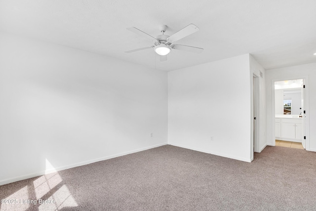 carpeted empty room featuring baseboards and a ceiling fan