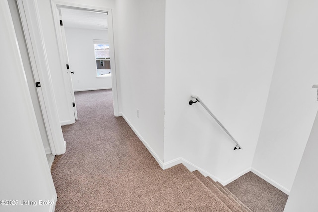 hallway with baseboards, carpet flooring, and an upstairs landing