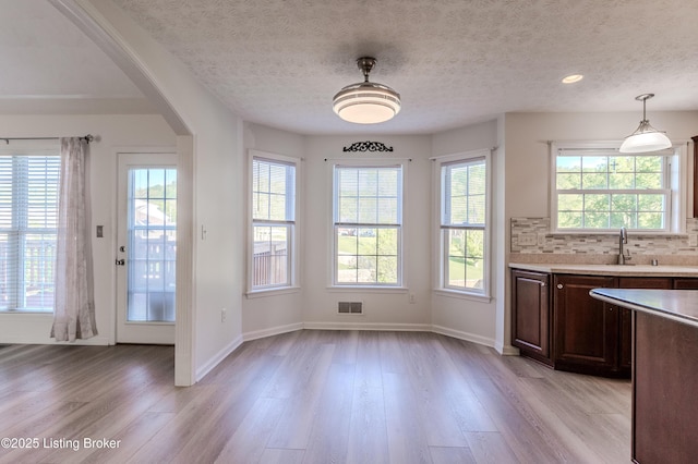 5503 Vevia Pl, Louisville, KY 40272 - unfurnished dining area featuring light wood-style floors, arched walkways, baseboards, a textured ceiling, and a sink