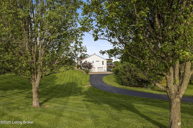 exterior space featuring aphalt driveway and a yard
