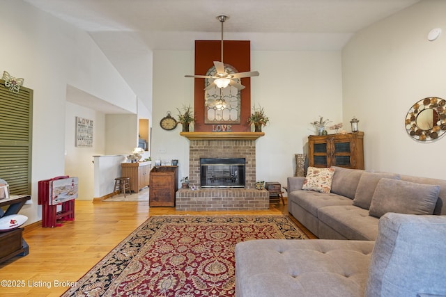 living area with ceiling fan, a fireplace, and wood finished floors