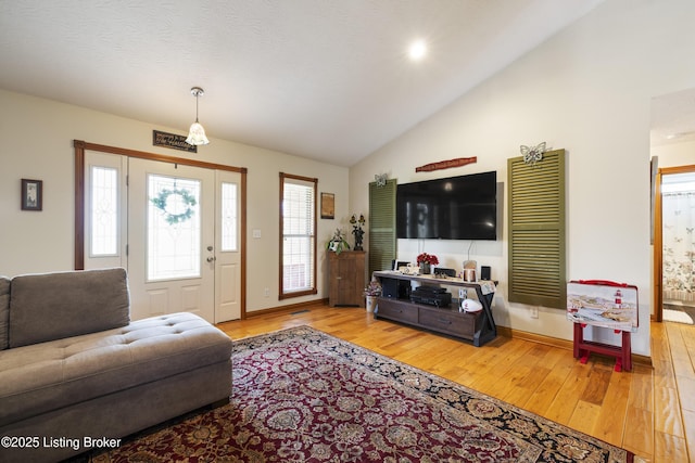 living area with baseboards, vaulted ceiling, and hardwood / wood-style flooring