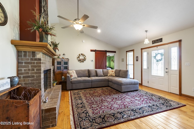 living room featuring wood-type flooring, a ceiling fan, a barn door, and lofted ceiling