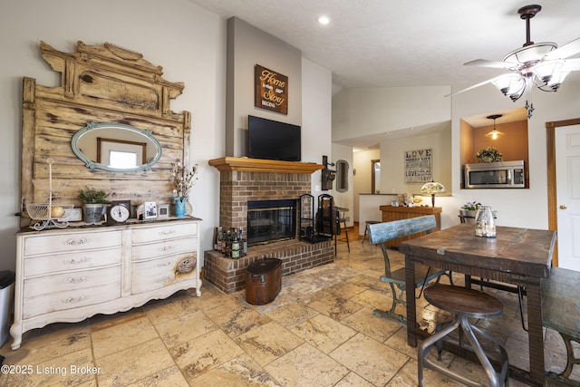 interior space with ceiling fan, a fireplace, recessed lighting, vaulted ceiling, and stone tile flooring