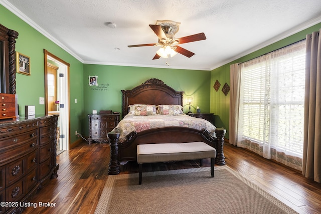 bedroom with dark wood-type flooring, a ceiling fan, baseboards, and crown molding