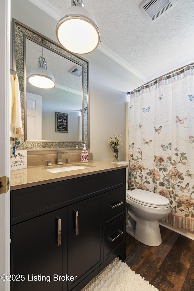 bathroom featuring visible vents, crown molding, wood finished floors, and toilet