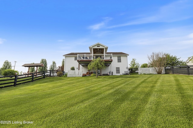 back of house with a lawn, a fenced backyard, and a balcony