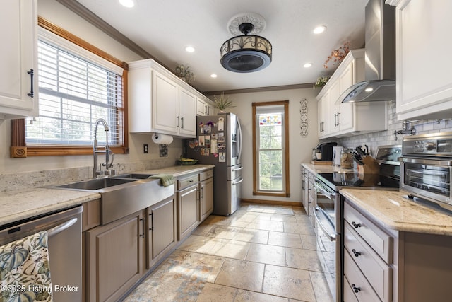 kitchen with stone tile floors, recessed lighting, wall chimney exhaust hood, a sink, and stainless steel appliances