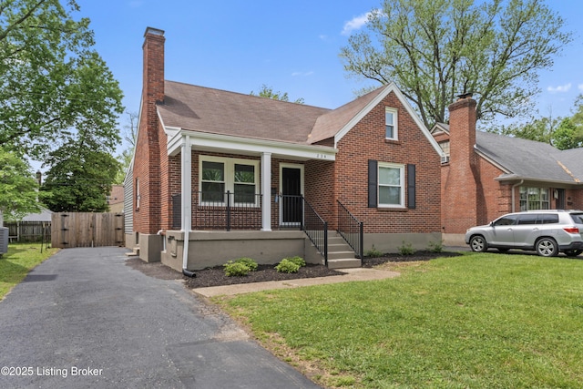 bungalow-style house with a porch, a gate, a front yard, and a chimney