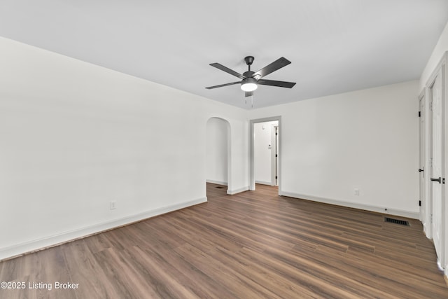 unfurnished bedroom featuring arched walkways, baseboards, visible vents, and wood finished floors