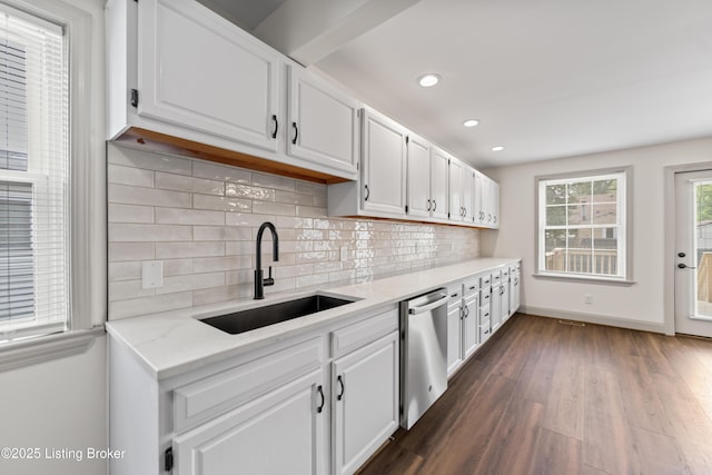 kitchen with stainless steel dishwasher, white cabinetry, a sink, and tasteful backsplash
