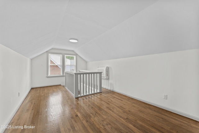 bonus room featuring baseboards, vaulted ceiling, a wall unit AC, and hardwood / wood-style flooring