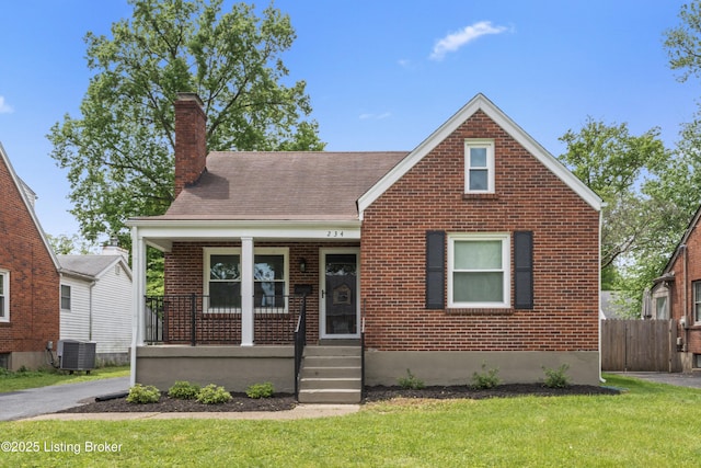 bungalow-style house with covered porch, a chimney, brick siding, fence, and a front lawn