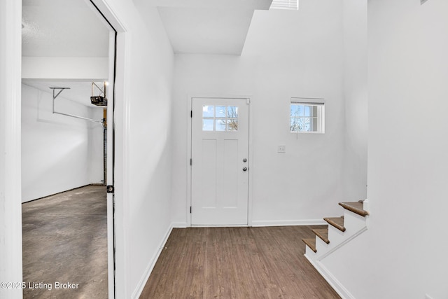 foyer entrance featuring baseboards, stairs, and wood finished floors