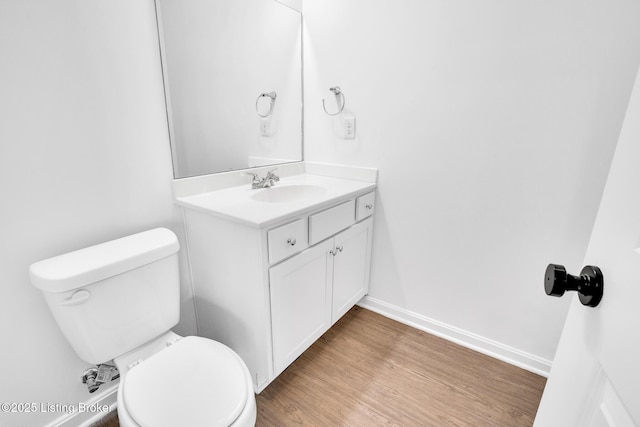bathroom with vanity, baseboards, wood finished floors, and toilet