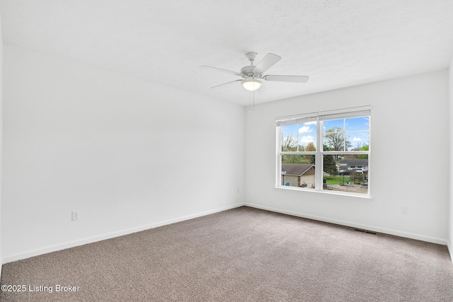 carpeted spare room with baseboards, ceiling fan, and visible vents