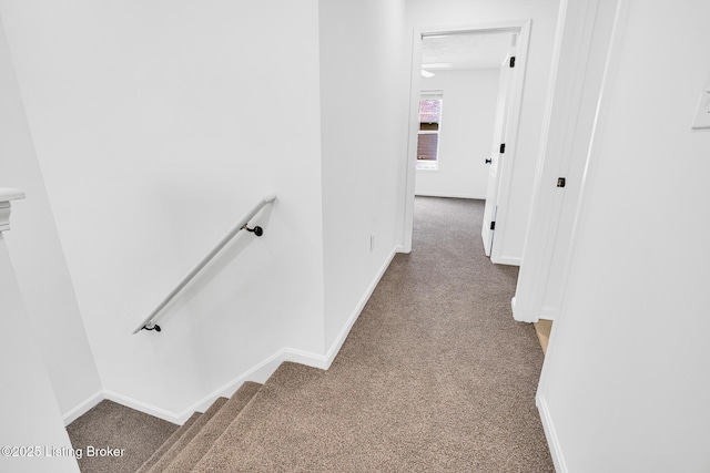 hall featuring carpet floors, baseboards, and an upstairs landing