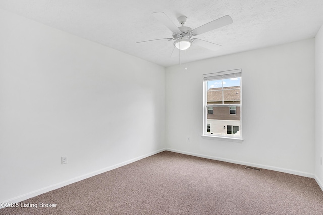 carpeted spare room with baseboards, ceiling fan, and visible vents