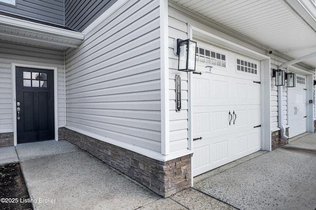 entrance to property with a garage and stone siding