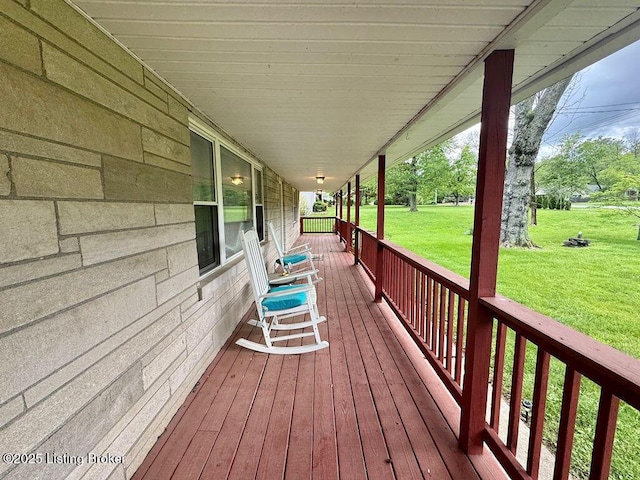 wooden terrace featuring a porch and a lawn