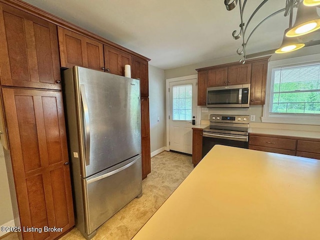 kitchen with appliances with stainless steel finishes, light countertops, brown cabinetry, and baseboards