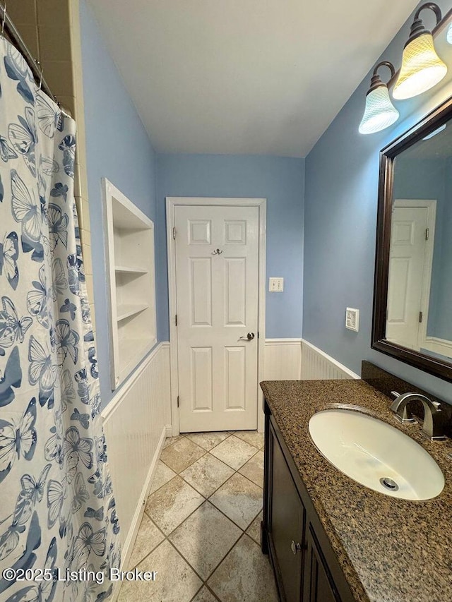 full bathroom with a wainscoted wall, vanity, built in features, and a shower with curtain