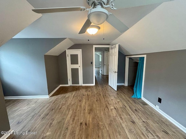 additional living space featuring wood finished floors, a ceiling fan, vaulted ceiling, and baseboards