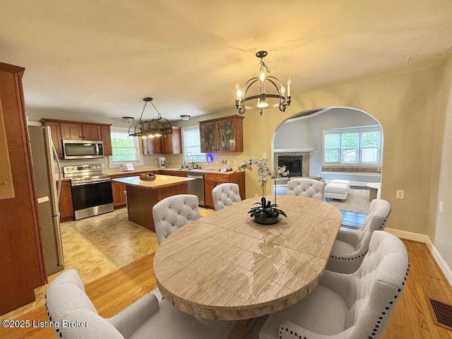 dining area with a chandelier, light wood-style flooring, baseboards, and a fireplace
