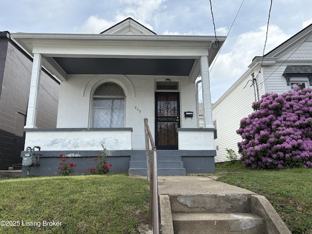 view of front facade featuring covered porch, brick siding, and a front yard
