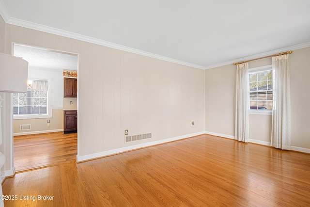 unfurnished room featuring visible vents, ornamental molding, and light wood-style floors