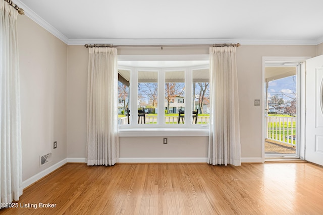 empty room with baseboards, ornamental molding, wood finished floors, and visible vents