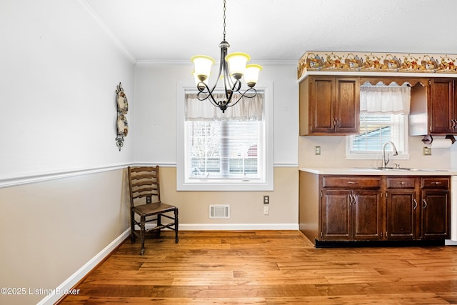 kitchen featuring visible vents, light countertops, a chandelier, a sink, and light wood-style flooring
