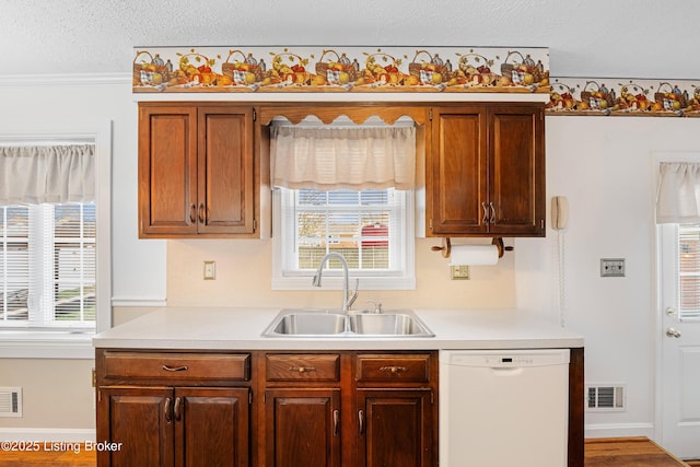 kitchen featuring white dishwasher, light countertops, a sink, and visible vents