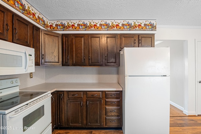 kitchen featuring dark brown cabinetry, a textured ceiling, wood finished floors, light countertops, and white appliances